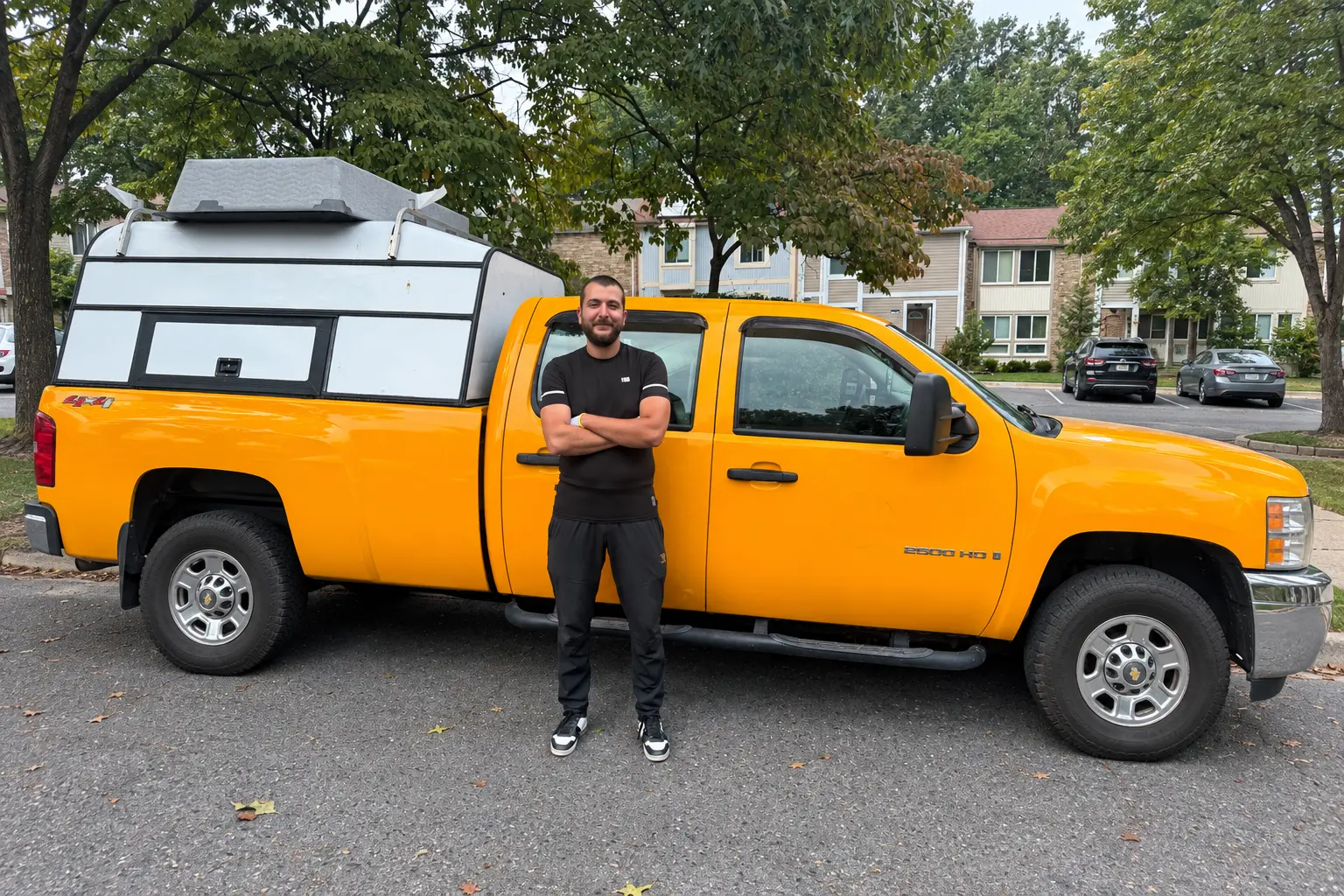 Dumpire LLC junk removal professional standing in front of a yellow hauling truck in Northern Virginia