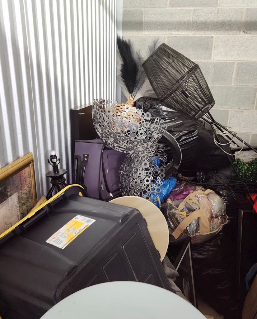 Furniture, boxes and household items inside a storage unit before a Dumpire LLC cleanout